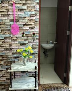 ein Badezimmer mit einem Waschbecken und einer Vase aus Blumen auf dem Tisch in der Unterkunft Alabang Staycation in Manila