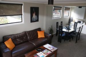 a living room with a leather couch and a table at 73 Milton Accommodation in Cambridge