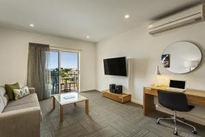 a living room with a couch and a desk with a laptop at Quest Townsville on Eyre in Townsville