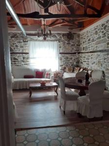 a living room with a table and a stone wall at Ξυλοπετρα / Wood & stone house in Tsagarada