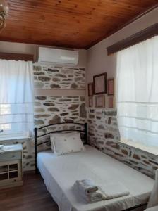 łóżko w pokoju z kamienną ścianą w obiekcie Ξυλοπετρα / Wood & stone house w mieście Tsagarada