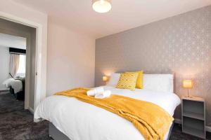 een slaapkamer met een groot bed en een gele deken bij CLOUDSTAYS - Luxury Townhouse Sleeps upto 8 Birmingham City and Central Free Parking & WIFI in Birmingham