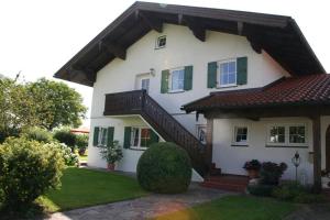 a white house with a brown roof and green shutters at Ferienwohnung Heimatglück 2-3 Personen 65qm WLAN in Breitbrunn am Chiemsee