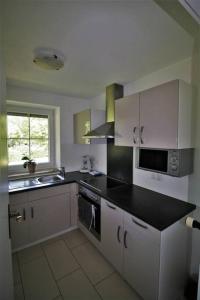a kitchen with white cabinets and a black counter top at Ferienwohnung Heimatglück 2-3 Personen 65qm WLAN in Breitbrunn am Chiemsee