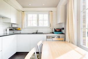 a kitchen with white cabinets and a wooden table at Private Room in a beautiful Villa in Ghent