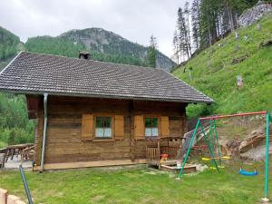 a wooden cabin with a playground in front of it at Siegel Almhütte in Zederhaus