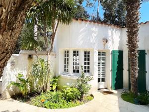 una casa blanca con una puerta verde y palmeras en Studio with beautiful private garden on the forest in Domino, en Les Sables Vignier