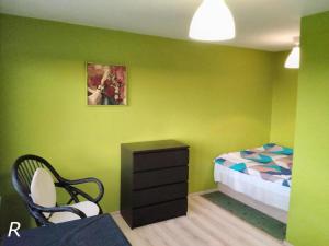 um quarto com paredes verdes e uma cama e uma cadeira em Panoramic views na Cracóvia