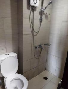 een badkamer met een douche, een toilet en een douche bij Staycation Alabang in Manilla