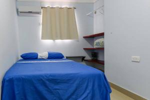 Habitación con cama con sábanas azules y ventana. en Apartamentos Katy, en San Andrés