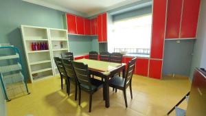 uma sala de jantar com armários vermelhos e uma mesa e cadeiras em Teratak Azhan Homestay em Kampong Sungai Putat