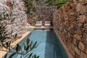 a pool with two pillows next to a stone wall at Citta dei Nicliani in Koíta