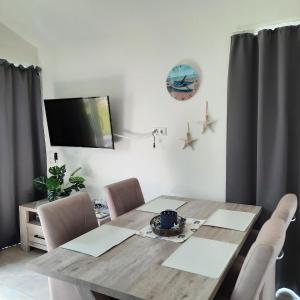 een eettafel met stoelen en een televisie aan de muur bij Seestern - Ferienhaus am Quendorfer See (Nr. 5) in Schüttorf