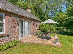 a patio with a table and an umbrella at Curlew Cottage in Meigle