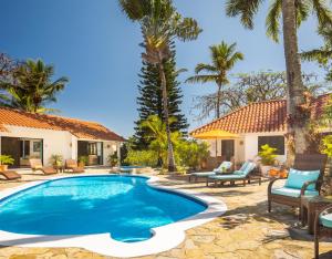 a swimming pool in a yard with palm trees at Garden By The Sea in Sosúa