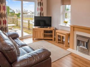 a living room with a leather couch and a television at Gatekeepers Cottage - Uk6728 in Lydstep