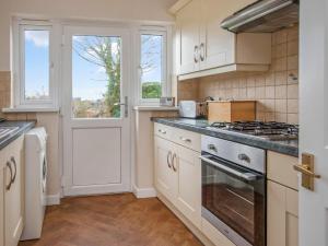 a kitchen with white cabinets and a stove top oven at Gatekeepers Cottage - Uk6728 in Lydstep