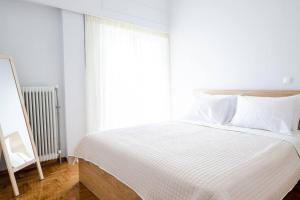 Schlafzimmer mit einem Bett mit weißer Bettwäsche und einem Fenster in der Unterkunft Cosy apartment 700m from Acropolis in Athen