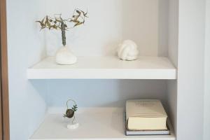 ein weißes Regal mit zwei Vasen und einem Buch in der Unterkunft Cosy apartment 700m from Acropolis in Athen