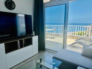 un soggiorno con divano, TV e balcone di AMADORES BALCONY - WITH OCEAN VIEW. ad Amadores