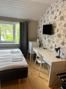 um quarto com uma cama, uma secretária e uma televisão em Norppa Resort em Savonlinna