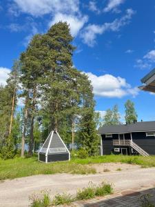 a house with a greenhouse next to a large tree at Norppa Resort in Savonlinna