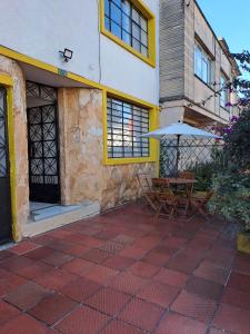 a patio with a table and an umbrella in front of a building at Makarena Hostel in Bogotá