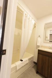 ein Badezimmer mit einer Dusche, einer Badewanne und einem Waschbecken in der Unterkunft Motel 7 Inn & Suites in Beresford