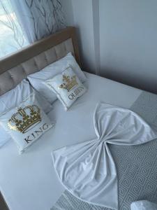 Una cama con sábanas blancas y almohadas. en Villa HENA, en Sarandë