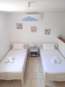 two beds in a room with white walls at Daphnes Apartments in Ratzaklíon