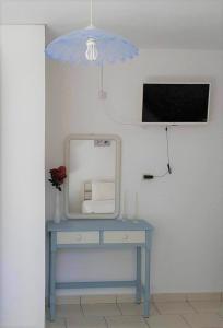 a blue table with a mirror and a tv on a wall at Daphnes Apartments in Ratzaklíon