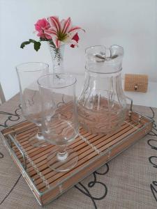 a tray with three glasses and a vase with a flower at Daphnes Apartments in Ratzaklíon