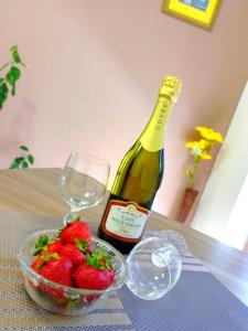 een fles wijn en een kom aardbeien op een tafel bij Apartman ELIT in Veliko Gradište
