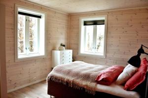 1 dormitorio con paredes de madera y 1 cama con almohadas rojas en Lille Herstrand - A unique seaside getaway, en Meløyskagen