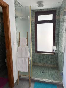 a bathroom with a shower with a window and a towel at Quinta do Rio Gerês in Bouro