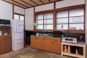 La cuisine est équipée d'un réfrigérateur blanc et d'un évier. dans l'établissement 一棟貸し古民家宿「縁側のとき」Engawanotoki Villa, 