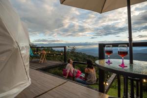 twee vrouwen aan een tafel met twee glazen wijn bij Refugio Mirador del Ocaso in Zipacón