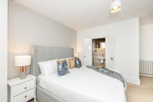 a white bedroom with a bed and a lamp at Stylish Apartment with BBQ Kensington in London