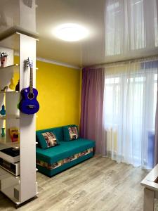 ein Wohnzimmer mit einer grünen Couch und einer Gitarre in der Unterkunft Яркая квартира в стиле Поп Арт в центре города Караганда in Qaraghandy