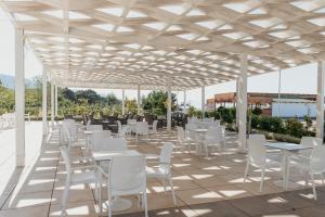 a group of white tables and chairs under a pavilion at Fishta Hotel & Apartments in Velipojë