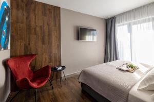 a hotel room with a bed and a red chair at Roof 69 Rooms in Split