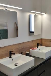 ein Badezimmer mit zwei weißen Waschbecken und einem Spiegel in der Unterkunft maison angles in Angles