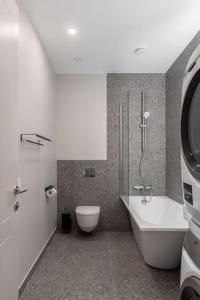 a bathroom with a toilet and a tub and a sink at OldTown&River View Hoffmann A4 in Rīga