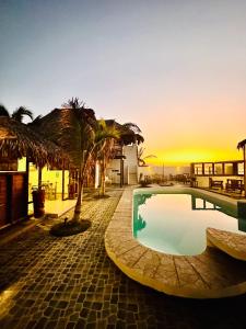 a resort with a pool and palm trees and the sunset at Hotel Puerto Antiguo in Los Órganos