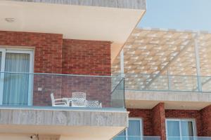 un balcone con sedia su un edificio in mattoni di Fishta Hotel & Apartments a Velipojë