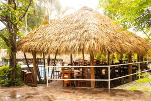 a straw hut with chairs and tables and a pool at Apart Hotel Acuarious de Luis in Estelí