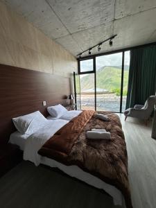 a bedroom with a large bed with a large window at Hotel NOA Kazbegi in Stepantsminda