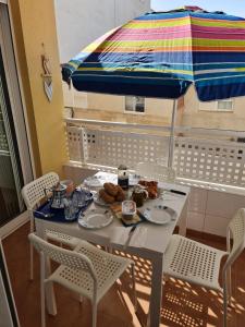 einen Tisch mit Essen und einen Regenschirm auf dem Balkon in der Unterkunft Luz de almoradi in Almoradí