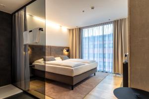 Pokój hotelowy z łóżkiem i szklaną ścianą w obiekcie arte Hotel Salzburg w mieście Salzburg
