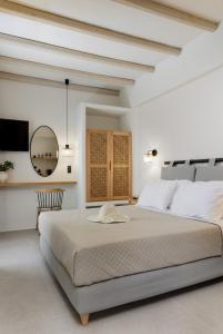 a white bedroom with a large bed and a mirror at Aesthete Suites in Agia Anna Naxos